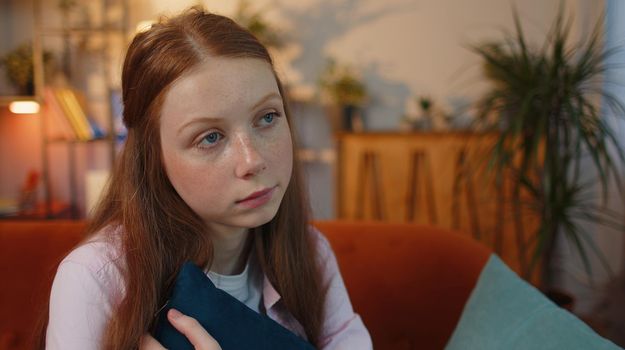 Portrait of sad young woman sitting at home looks pensive thinks over life concerns or unrequited love, suffers from unfair situation. Problem, break up, depressed girl feeling bad annoyed, burnout