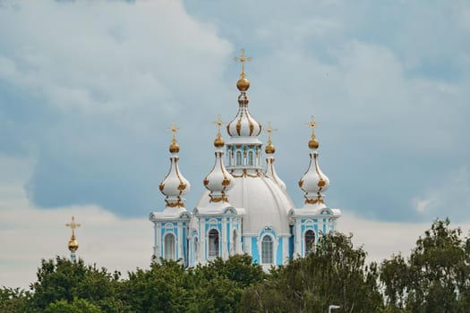golden domes and crosses of the Smolny Cathedral in sunny weather against the background of a gloomy sky. High quality photo