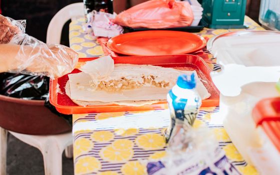 Homemade Nicaraguan quesillo, traditional large quesillo food. Hands making a Nicaraguan quesillo. Close up of hands making a traditional quesillo with pickled onion.