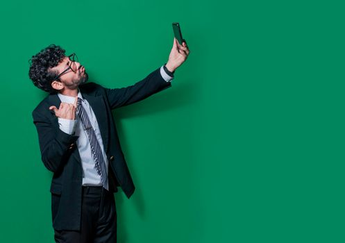 Young businessman taking a selfie with funny gestures, Businessman taking funny selfies isolated, Concept of businessman guy taking a selfie and blowing kisses on the cell phone