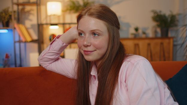 Portrait of happy calm young woman smiling friendly glad expression looking away dreaming resting, relaxation feel satisfied concept good news sitting on sofa at home room. Pretty girl falling in love