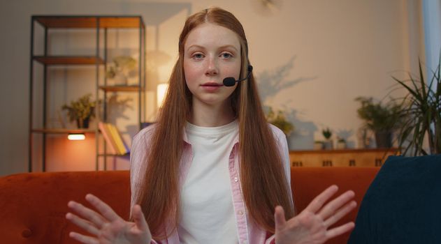 POV of teen young child girl wearing headset, freelance worker, call center or support service operator helpline, having talk with client or colleague communication support waving hello alone at home