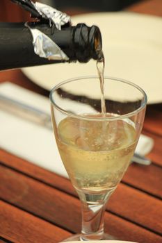 Man pouring white wine at a dinner table
