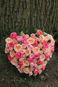 Heart shaped sympathy flowers  or funeral flowers near a tree