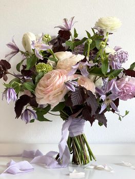 Wedding bouquet with a purple ribbon stands against the wall. High quality photo