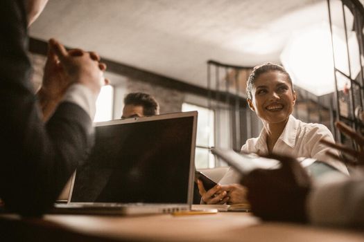 Discussion During Business Meeting Of Coworkers , Selective Focus On Smiling Caucasian Businesswoman Holding Phone, Bottom View Of Business People Working At Table With Computer On It, Toned Image