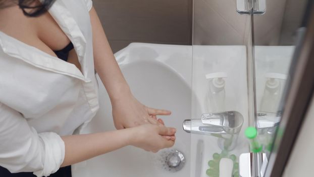 Sexy Lady washing hands, Young Woman Removes Water From Her Fingers Over White Ceramic Washbasin, She Washes Hands As Often As Possible During Quarantine, High Angle View