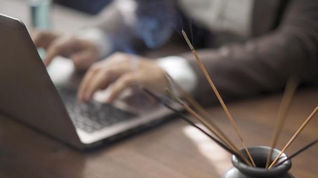 Business Woman Working On Laptop In Office During Pandemic Days, Close Up Of Female Hands Typing On A Computer Keyboard, Selective Focus On Incense Sticks In Foreground