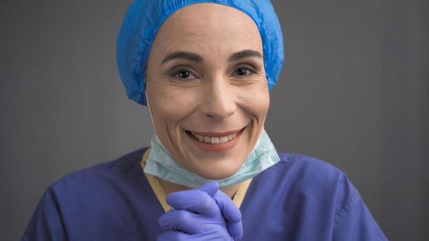 Female Medical Worker Smiling Happily Rejoicing In Good News, Doctor In Blue Uniform Took Off Her Mask While Looking At Camera, Quarantine Concept