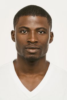 Attractive African american man looking seriously at the camera, Dark-skinned guy in a white t-shirt on a white background looks confident, cut out on white. Toned image.