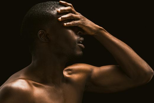 African facepalm. Sexy African man covered his face with his hand, profile view of a naked African american young guy posing on black background touching his face with his hand, Toned image.