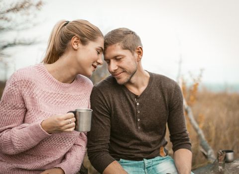 Happy Couple In Love Touched Their Foreheads, Portrait Of Man And Woman Gently Touching Foreheads To Each Other Closing Eyes, Blonde Holding Metal Cup With Hot Drinks, Tenderness In Nature Concept