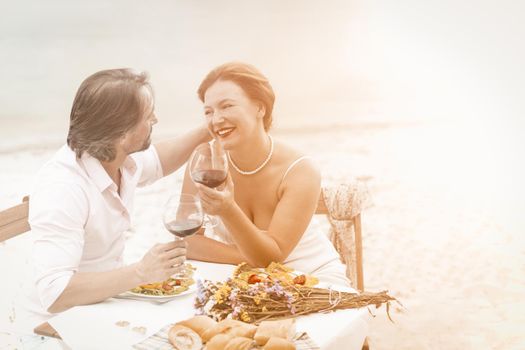 Mid aged couple with red wine sit in restaurant in beautiful style. Happy elderly concept.