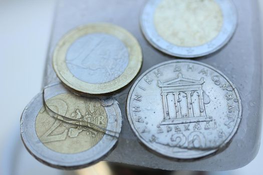 Frozen Assets: Greek euro and Drachme coins in ice