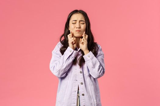 Portrait of woman desperately wants her dream to come true, cross fingers and close eyes, pouting pleading, praying god wish fulfill, standing pink background anticipate miracle happen with hope.
