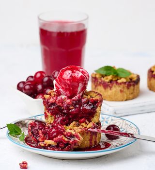 Cherry crumble pie decorated with a scoop of ice cream and drizzled with cherry sauce on a plate