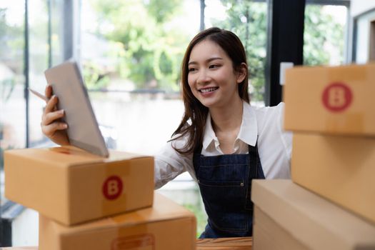 Attractive Asian entrepreneur business woman checking order by tablet.