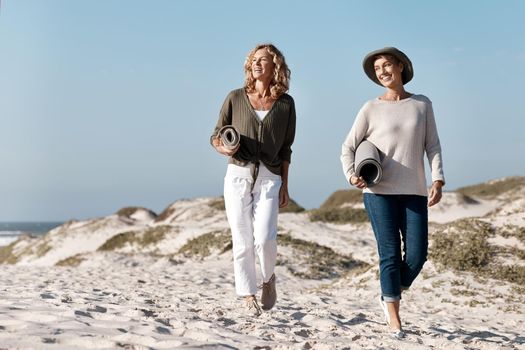 Its the perfect day for a trip to the beach. Full length shot of two attractive mature woman walking with their on the beach