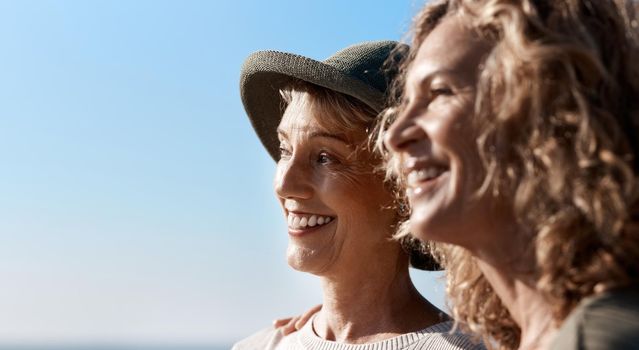 Taking in the views. two attractive mature women standing on the beach