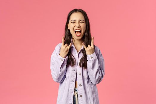 This festival rocks. Enthusiastic, excited good-looking girl having fun on awesome concert, show rock-n-roll heavy metal sign screaming from joy and thrill, standing pink background.