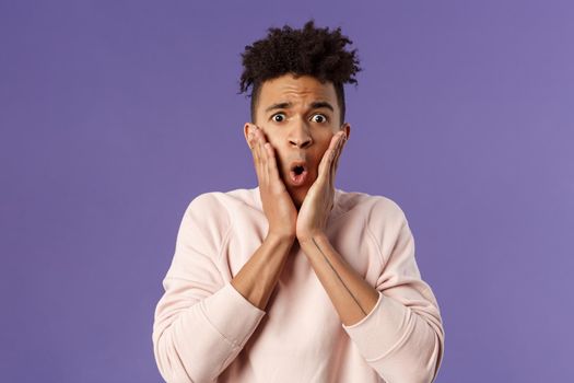 Close-up portrait of concerned, embarrassed young man hold hands on cheeks looking desperate and alarmed, feel worried about first date, being indecisive dont know what do.