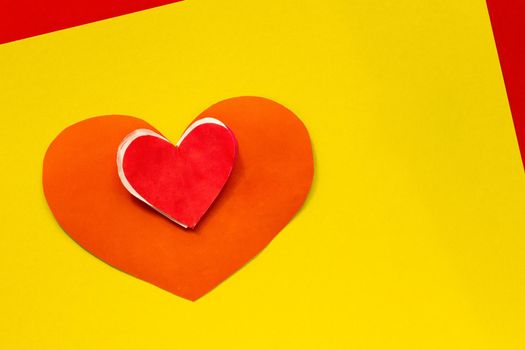 Top view of diy red heart made by child on yellow background