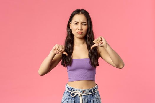 Awful party mate. Portrait of disappointed, picky young stylish girl dislike something bad, show thumbs-down, grimacing and pouting from disappointment, leave negative comment.