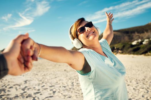 Life is more beautiful when you live it with a positive attitude. a woman wearing headphones and enjoying herself at the beach