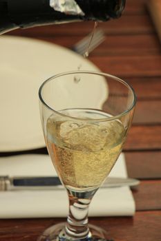 Man pouring white wine at a dinner table