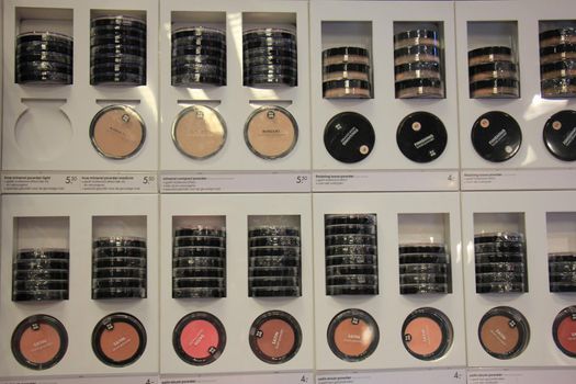 Compact powders and blush on display in a drugstore. (text on display: product information in both English and Dutch)