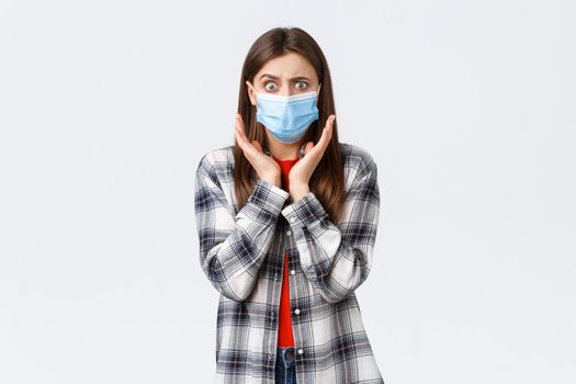 Coronavirus outbreak, leisure on quarantine, social distancing and emotions concept. Concerned and shocked young woman hear bad news. Girl in medical mask gasping and looking worried camera.