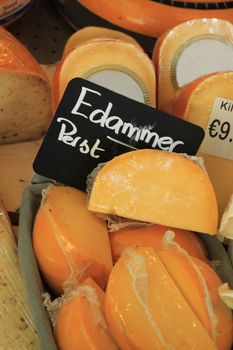 Traditional Dutch cheeses on display in a store (text on labels: price and product information in Dutch, the famous Edammer cheese)