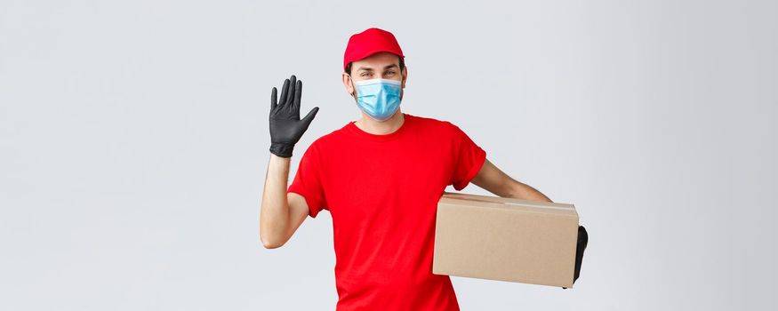 Packages and parcels delivery, covid-19 quarantine delivery, transfer orders. Friendly courier in red uniform, face mask with protective gloves, deliver order box to client, waving hand in hello.