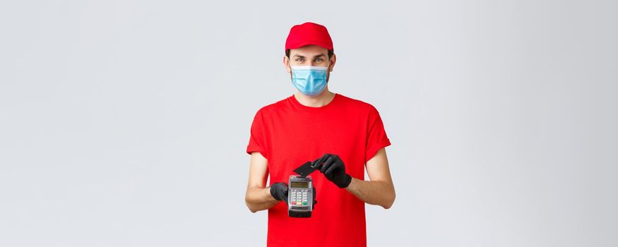 Contactless delivery, payment and online shopping during covid-19, self-quarantine. Courier provide safe paying orders, buying with credit card pressed to POS terminal, wear face mask and gloves.