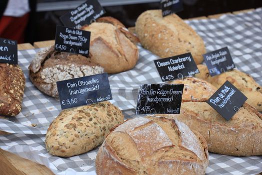 Luxury artisanal bread at a market (text on tags: product and price information in Dutch, sourdough with cranberries or lemon)