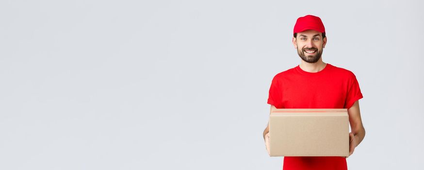 Order delivery, online shopping and package shipping concept. Smiling friendly courier bring package to client doorstep. Employee in red service cap and t-shirt holding box, parcel for customer.