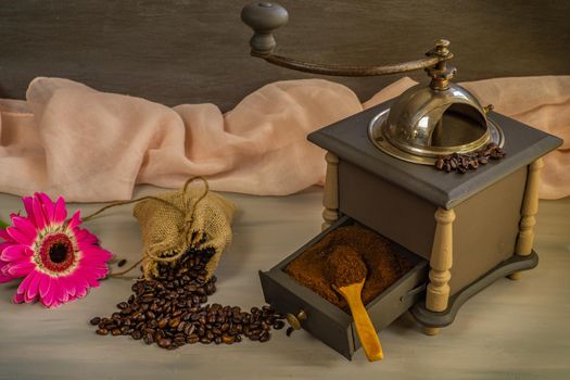 coffee beans and ground coffee with coffee grinder and flowers