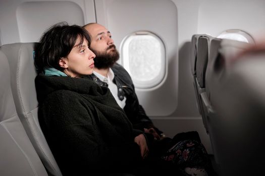 Caucasian travellers having conversation on commercial flight, travelling by plane to go on holiday journey destination. Couple flying abroad with airplane transport to arrive on vacation.