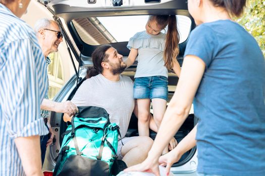 Caucasian family travelling on holiday vacation with little child, parents and grandparents. Going on summer journey at seaside with inflatable and travel bags, leaving with luggage and suitcase.