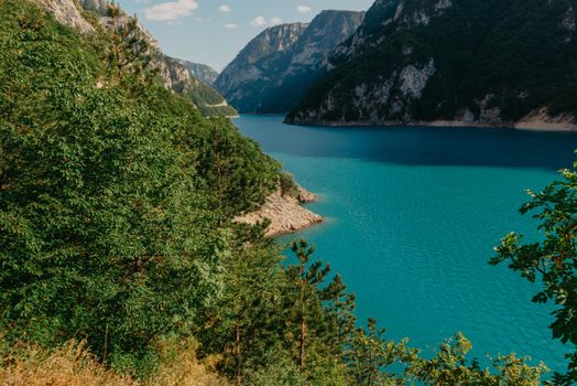 The concept of eco-tourism and active recreation. National Park. Mountain Emerald lake in the wooded mountains. Sunny day in autumn.