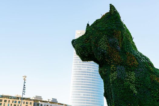 BILBAO, SPAIN-DECEMBER 18, 2021 : Puppy stands guard at Guggenheim Museum in Bilbao, Biscay, Basque Country, Spain. Landmarks. Dog sculpture of artist Jeff Koons. The World’s largest flower sculpture.
