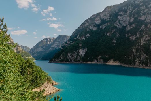 The concept of eco-tourism and active recreation. National Park. Mountain Emerald lake in the wooded mountains. Sunny day in autumn.