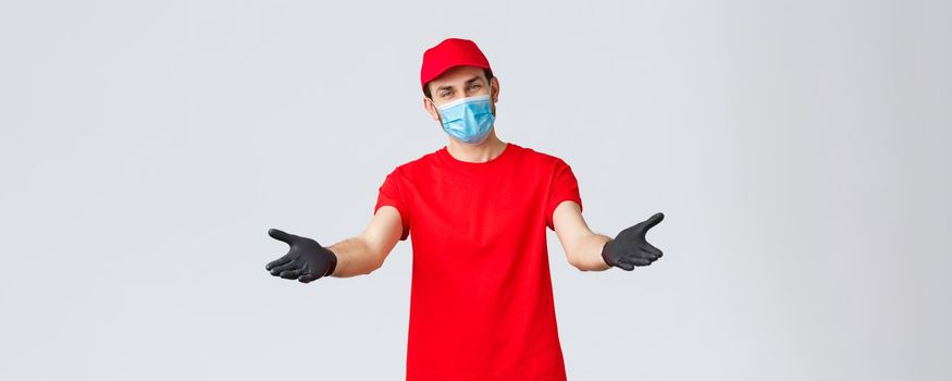 Covid-19, self-quarantine, online shopping and shipping concept. Friendly delivery man in face mask and gloves, reaching hands to receive package from client, provide delivering during coronavirus.