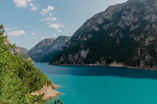 The concept of eco-tourism and active recreation. National Park. Mountain Emerald lake in the wooded mountains. Sunny day in autumn.