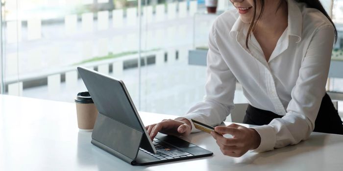 Young Asian businesswoman enjoy shopping online using credit card at a coffee shop..