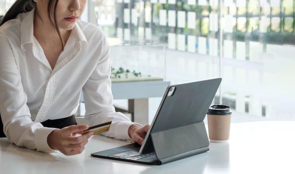 Young Asian businesswoman enjoy shopping online using credit card at a coffee shop..