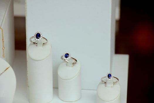Classic Diamond engagement rings in a shop window, blue sapphire with diamond halo