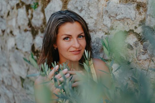 Girl tourist walking through ancient narrow street on a beautiful summer day in MEDITERRANEAN MEDIEVAL CITY , OLD TOWN bUDVA, MONTENEGRO. Young beautiful cheerful woman walking on old street at tropical town. Pretty girl looking at you and smiling