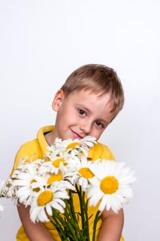 A cute boy with a beautiful bouquet of large daisies. Portrait of a child, funny and cute facial expression. Selective focus. A postcard for the celebration of the day of family, love and fidelity.