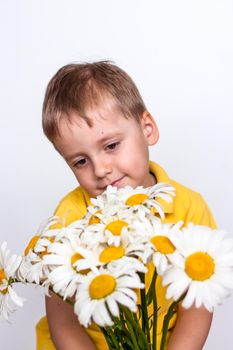 A cute boy with a beautiful bouquet of large daisies. Portrait of a child, funny and cute facial expression. Selective focus. A postcard for the celebration of the day of family, love and fidelity.